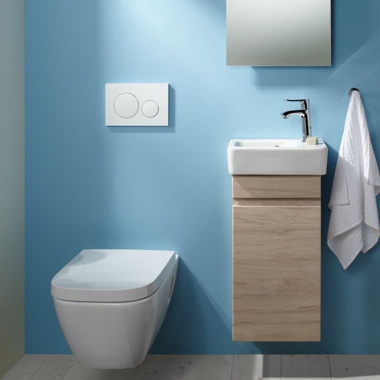 A wall-hung Renova Plan WC and a washbasin area attached to a light blue wall A wall-hung Renova Plan WC and a washbasin area attached to a light blue wall
